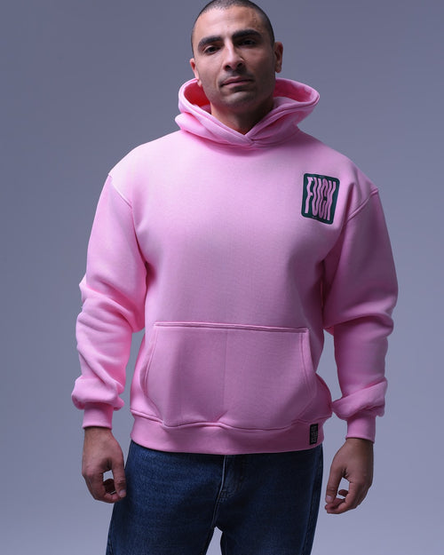Man wearing a pink oversized hoodie for unisex with front pocket and graphic logo on chest