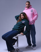 Two models wearing oversized hoodie for unisex in pink and dark green by NotYourSize2025