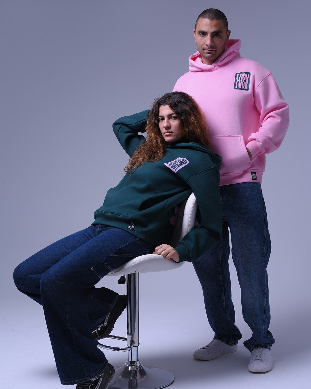 Two models wearing oversized hoodie for unisex in pink and dark green by NotYourSize2025