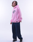 Girl wearing pink oversized hoodie for women with graphic print and dark loose jeans with headphones