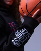 NotYourSize2025 oversized hoodie for women in black with bold sleeve text holding a basketball